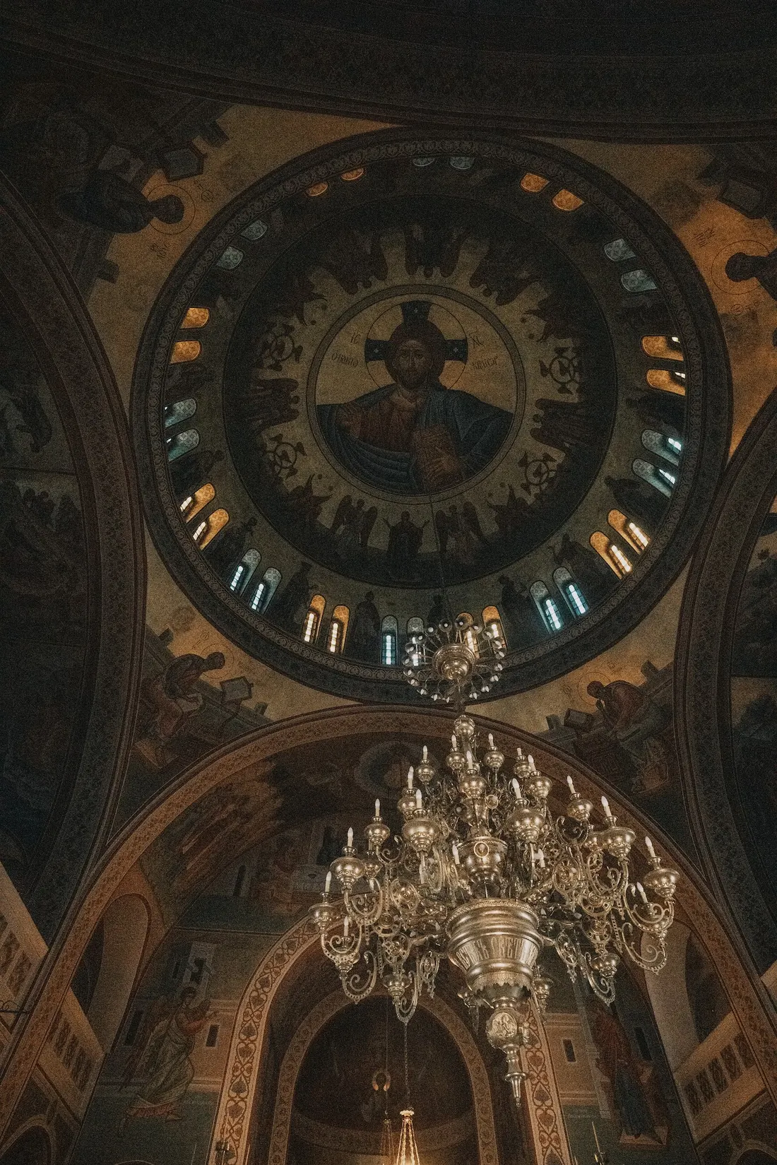 A painted church dome and chandelier photographed from below.