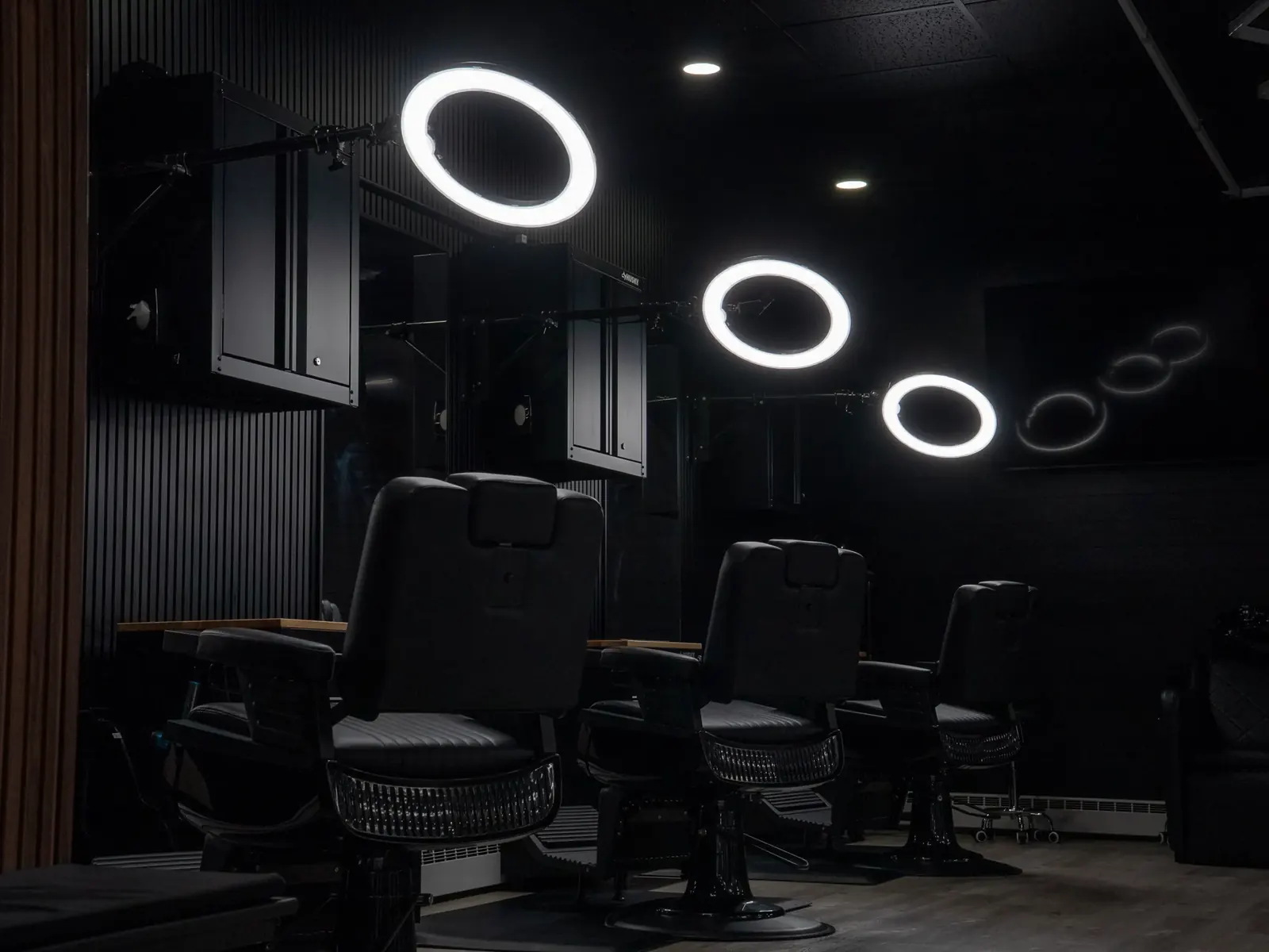 Row of black barber chairs under ring lights