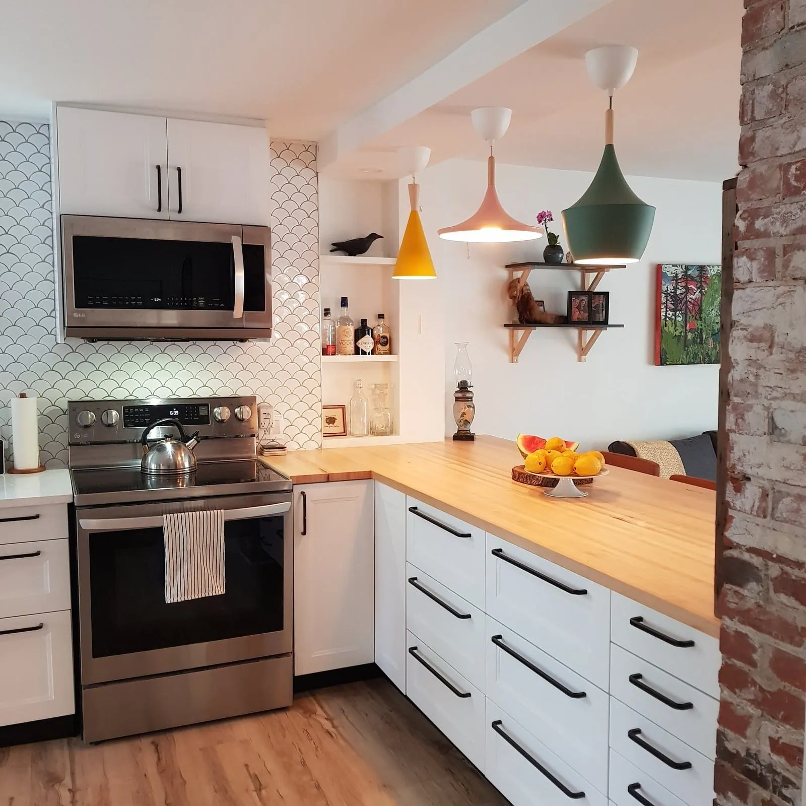 Brookside Kitchen: stainless range between white cabinets and open wood shelving