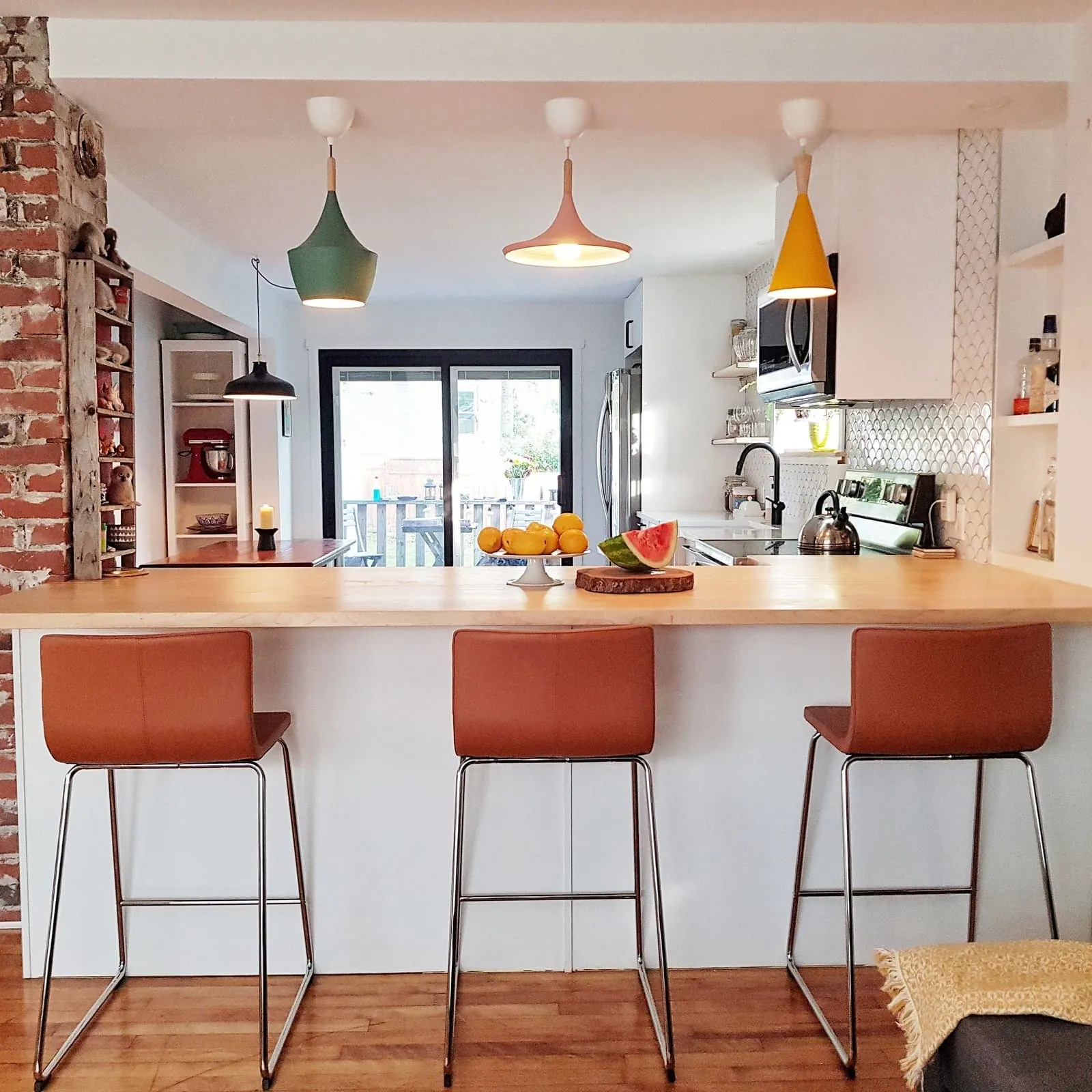 Brookside Kitchen: pendant lights over a peninsula with orange stools