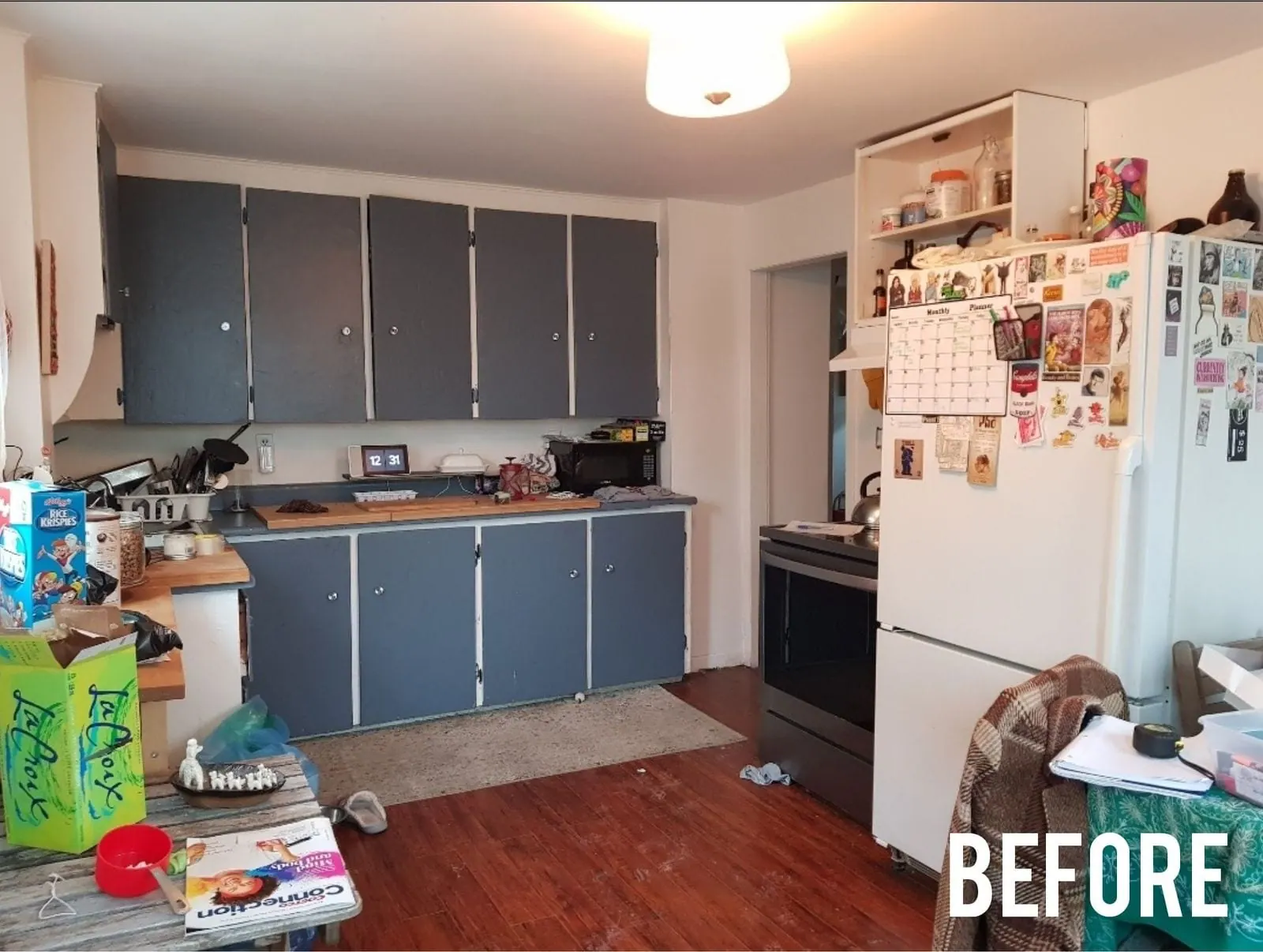Kitchen before: blue upper cabinets and a cluttered counter