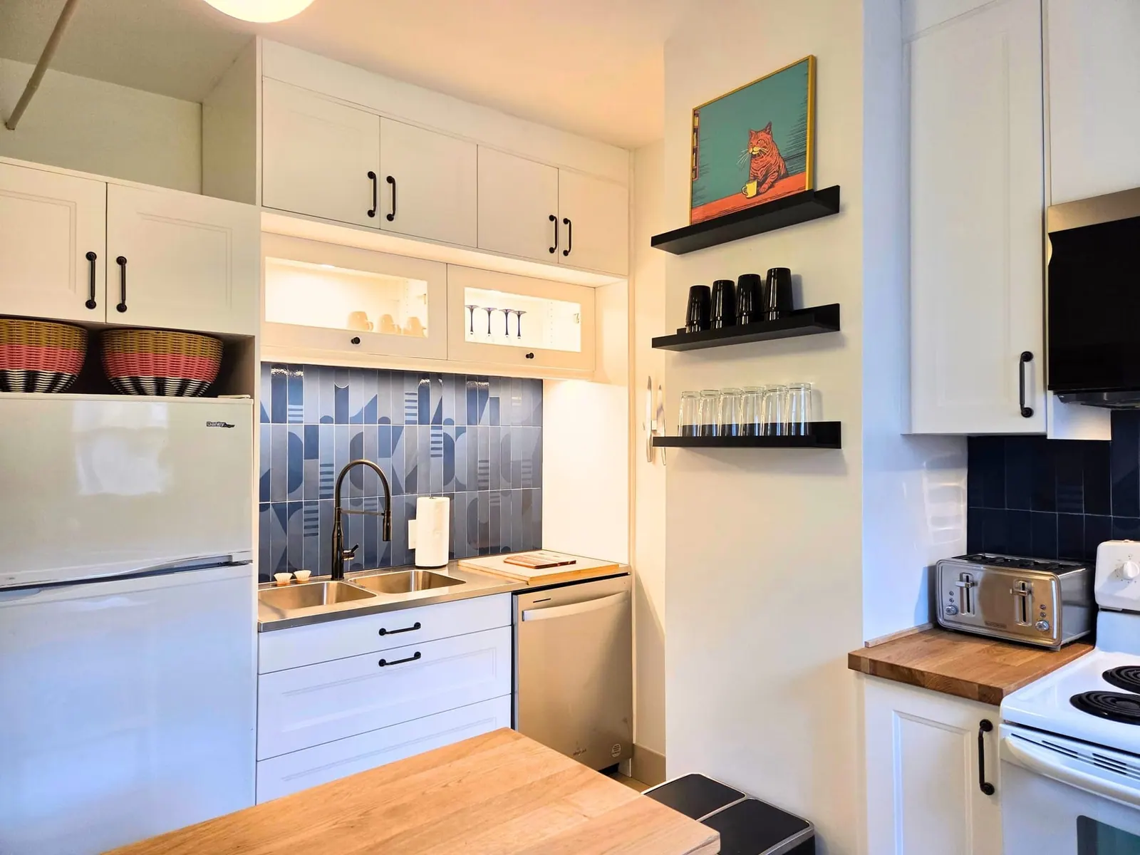 Compact white IKEA kitchen with blue tile, open black shelving and butcher-block counter