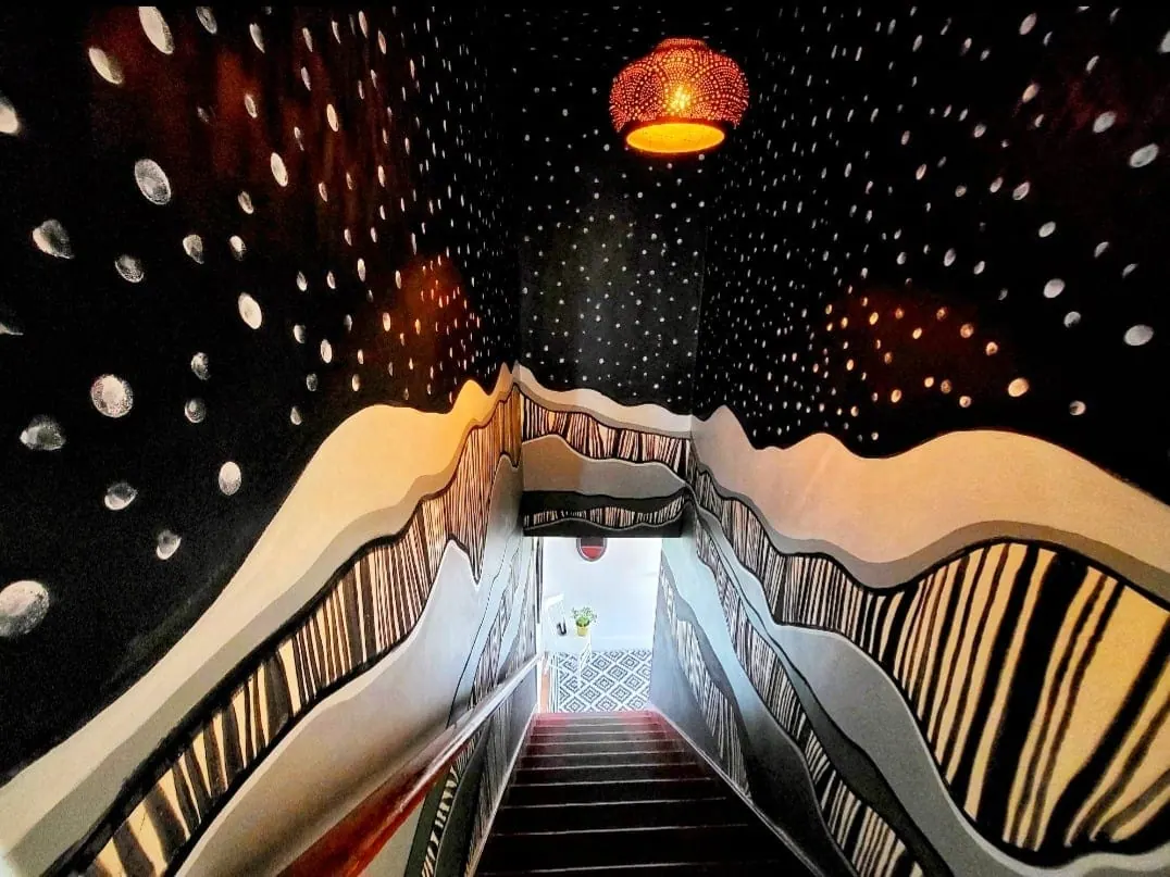 Stairwell after: star-dotted ceiling and striped mountain ridges down both walls