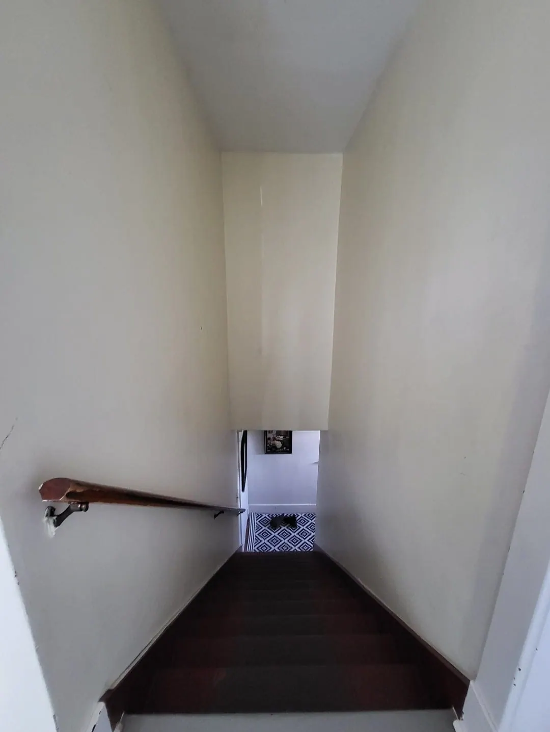 Stairwell before: plain white walls and a wooden handrail