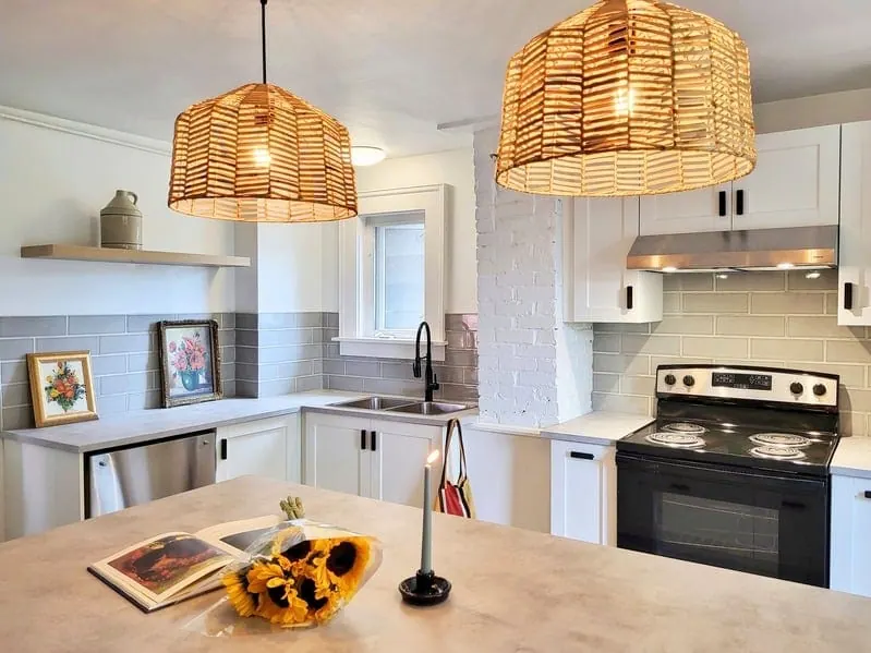 Kitchen with two woven pendant lamps over the island and a grey tile backsplash