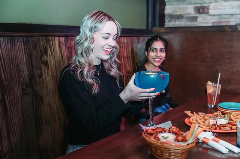 Guest raising a big blue bowl drink at Jungle Jim's