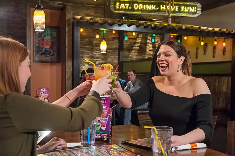 Guests cheersing cocktails under the neon sign