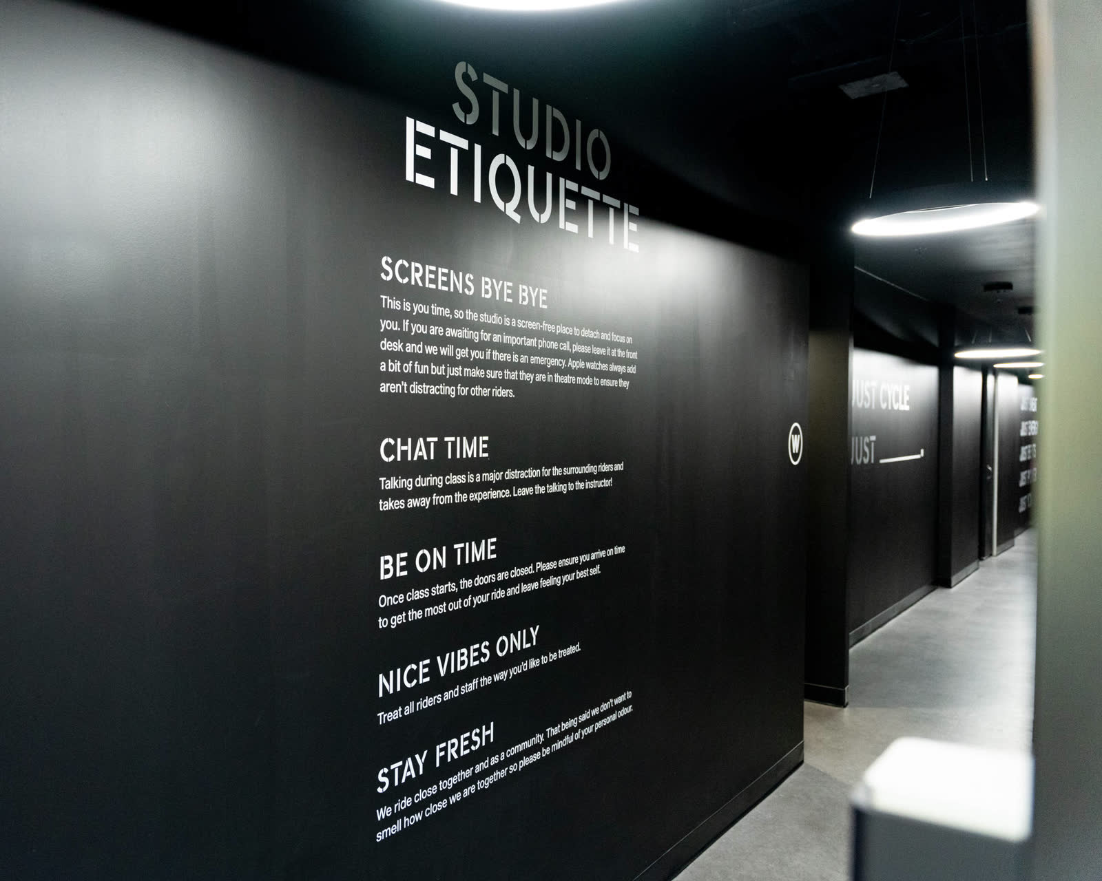 The studio's etiquette wall in the black corridor: screens, chat time, be on time, nice vibes only, stay fresh