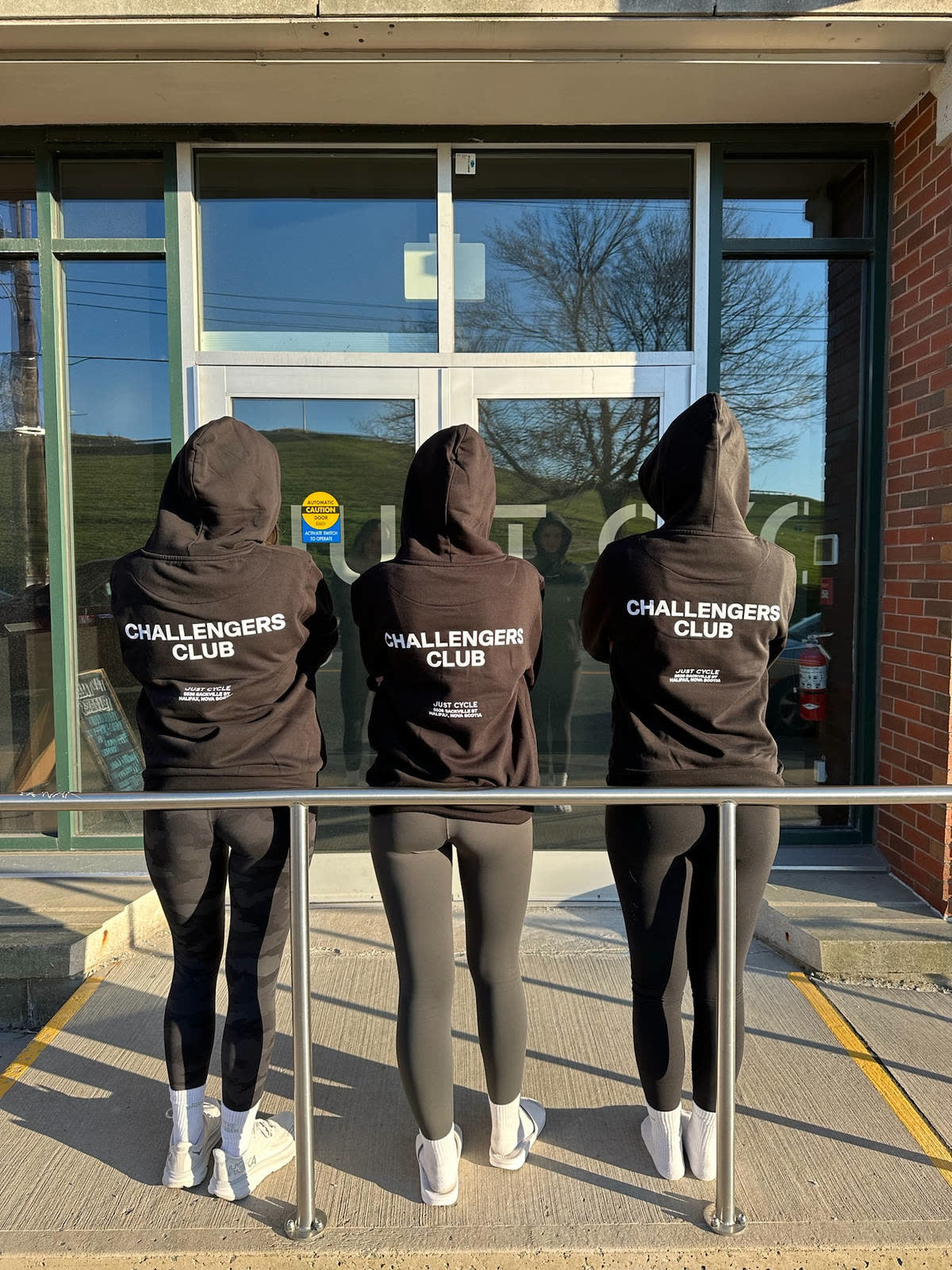 Three riders in matching hoodies at the studio entrance