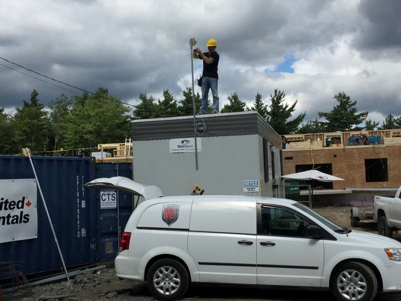 Technician standing on a site office trailer, installing a camera mast