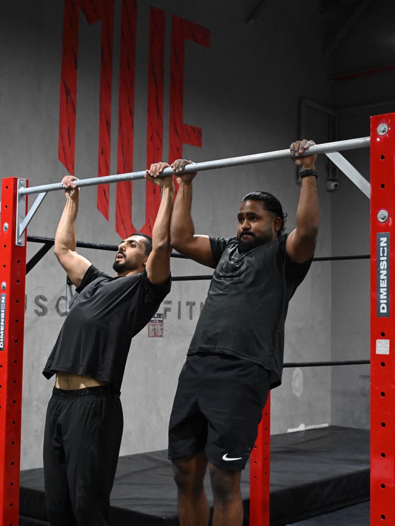 Two athletes pulling up side by side on the red rig