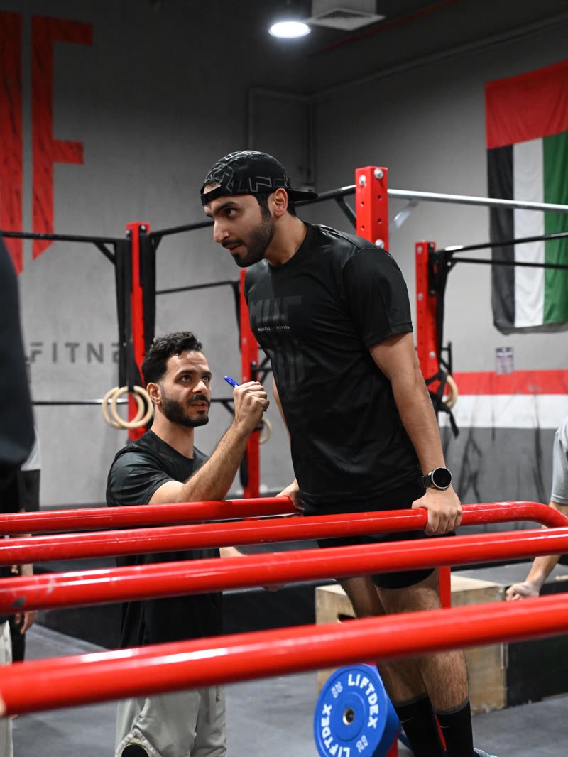 A coach counting an athlete’s dips on the red parallel bars