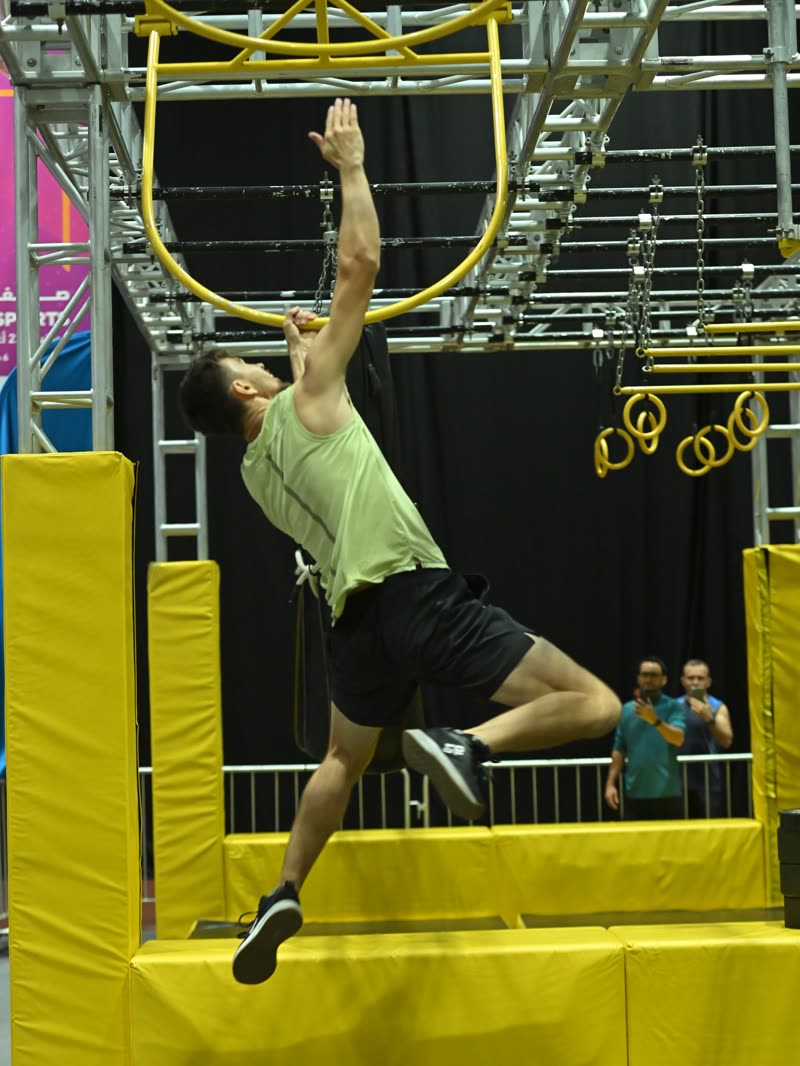 A competitor hanging from the ring holds on the ninja course
