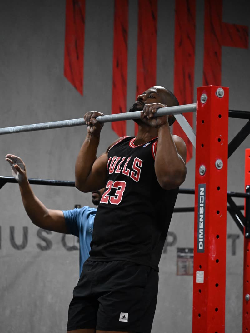 Pull-ups on the red rig in front of the MUF lettering on the gym wall