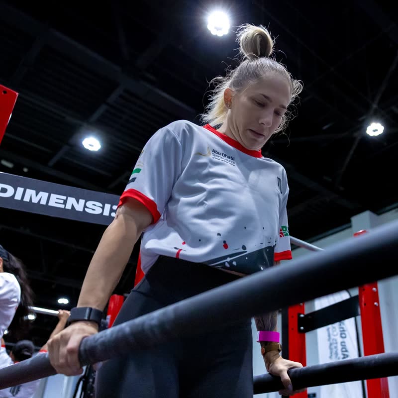 A competitor in a Reps Battles shirt on the low bar