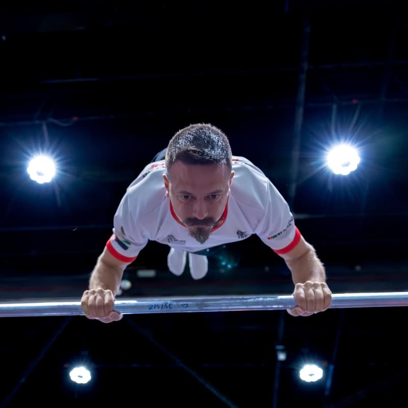 An athlete pressing into a planche lean over the bar