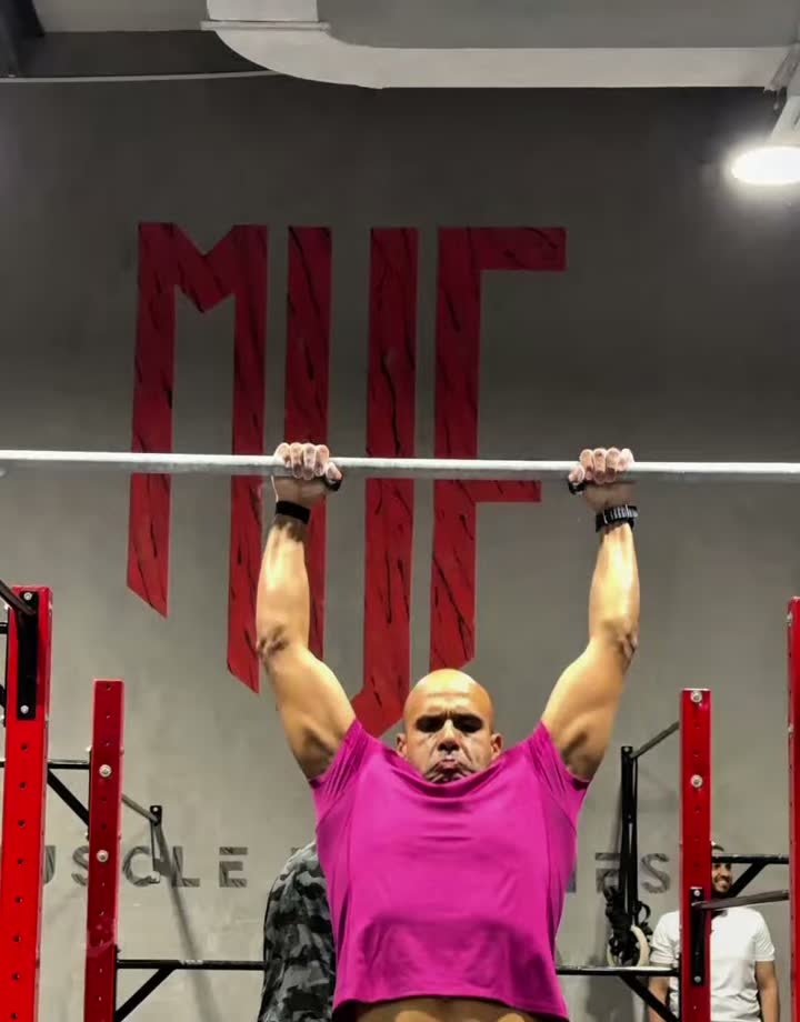 An athlete performing a muscle-up on the bar in front of the MUF lettering at Muscle Up Fitness