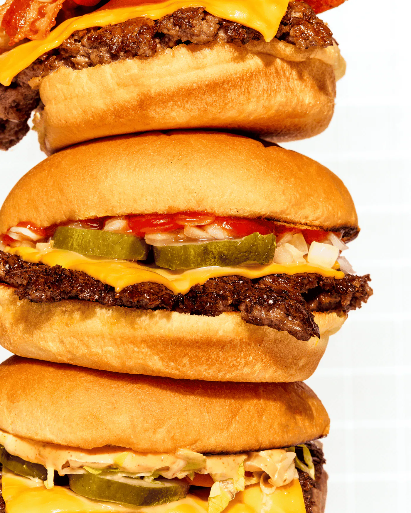 Three Rosie's double smashburgers stacked, cheese melting over the patties