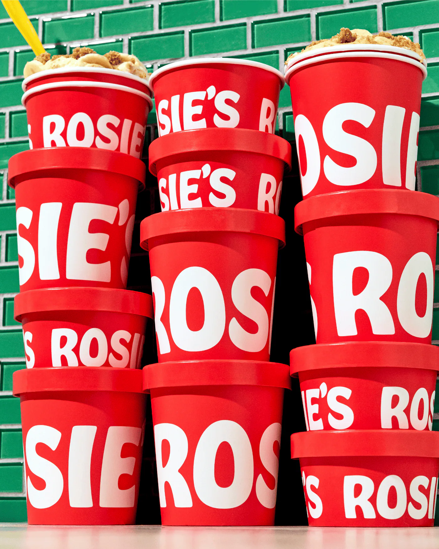Stacked red Rosie's cups against green tile