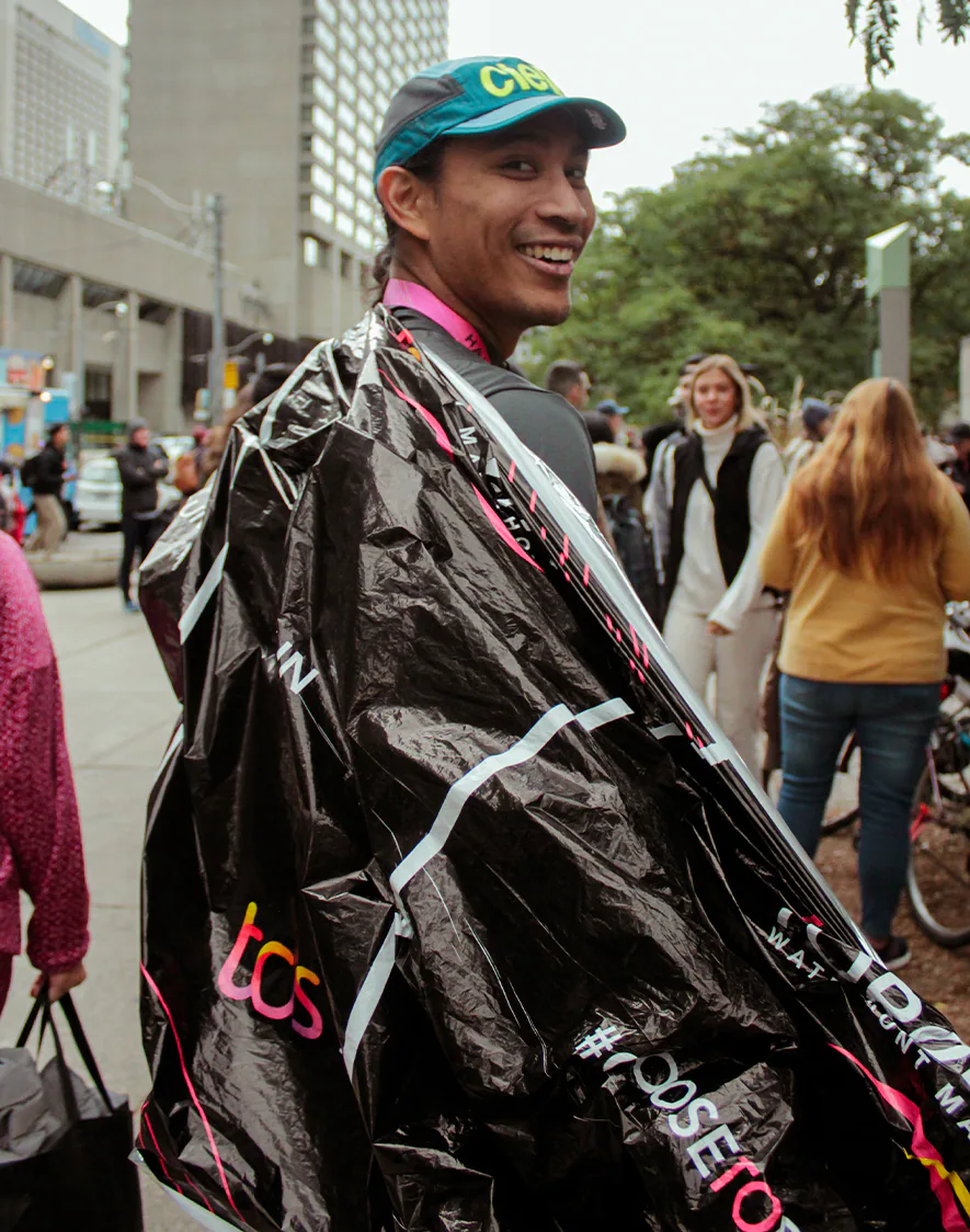 A runner smiles, wrapped in a black race poncho