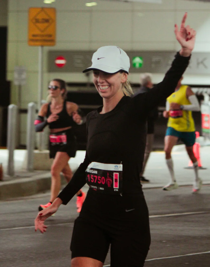 A runner waves to the crowd mid-race