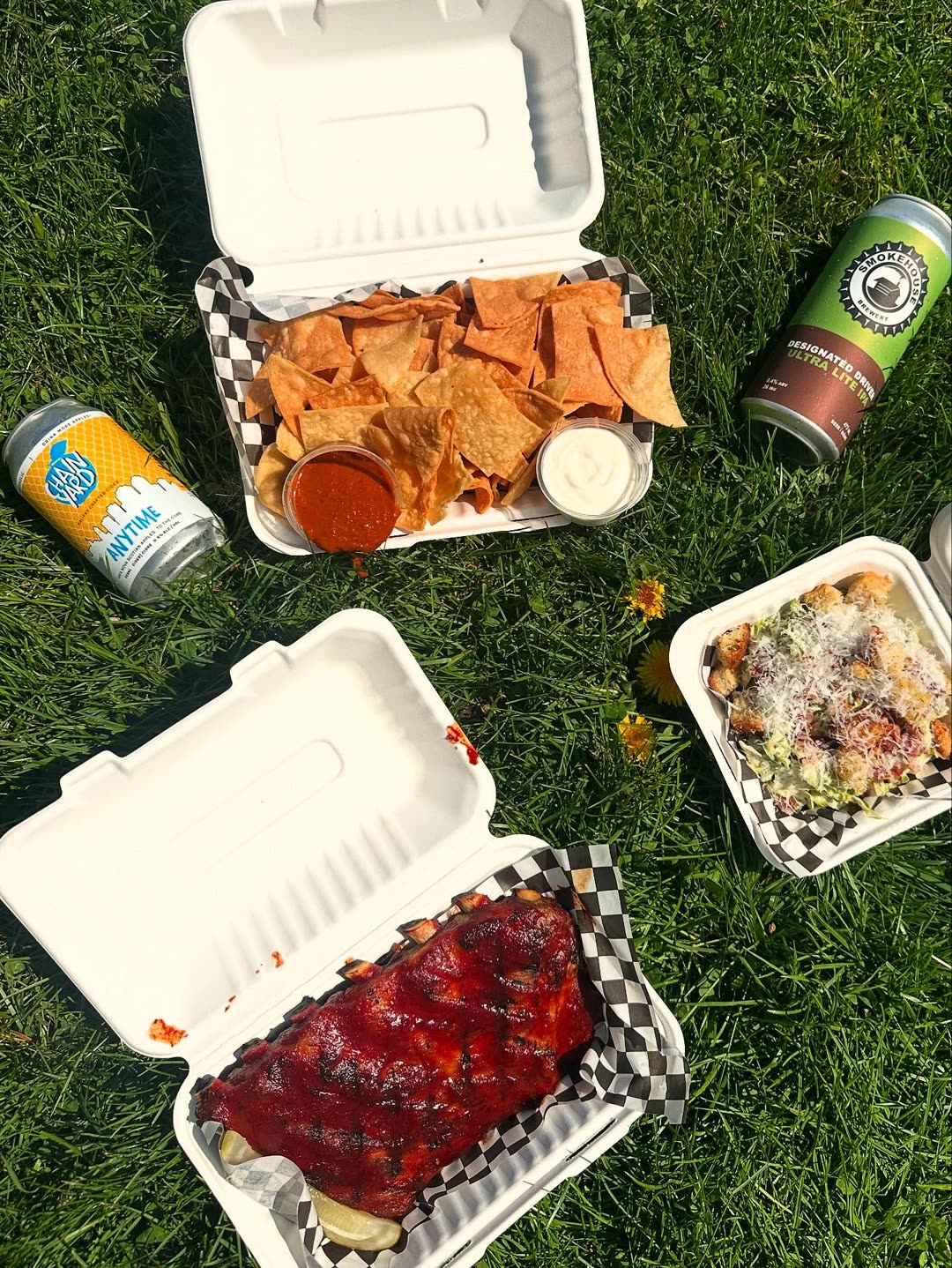 Bonfire take-out boxes and tall cans on the grass of the Commons