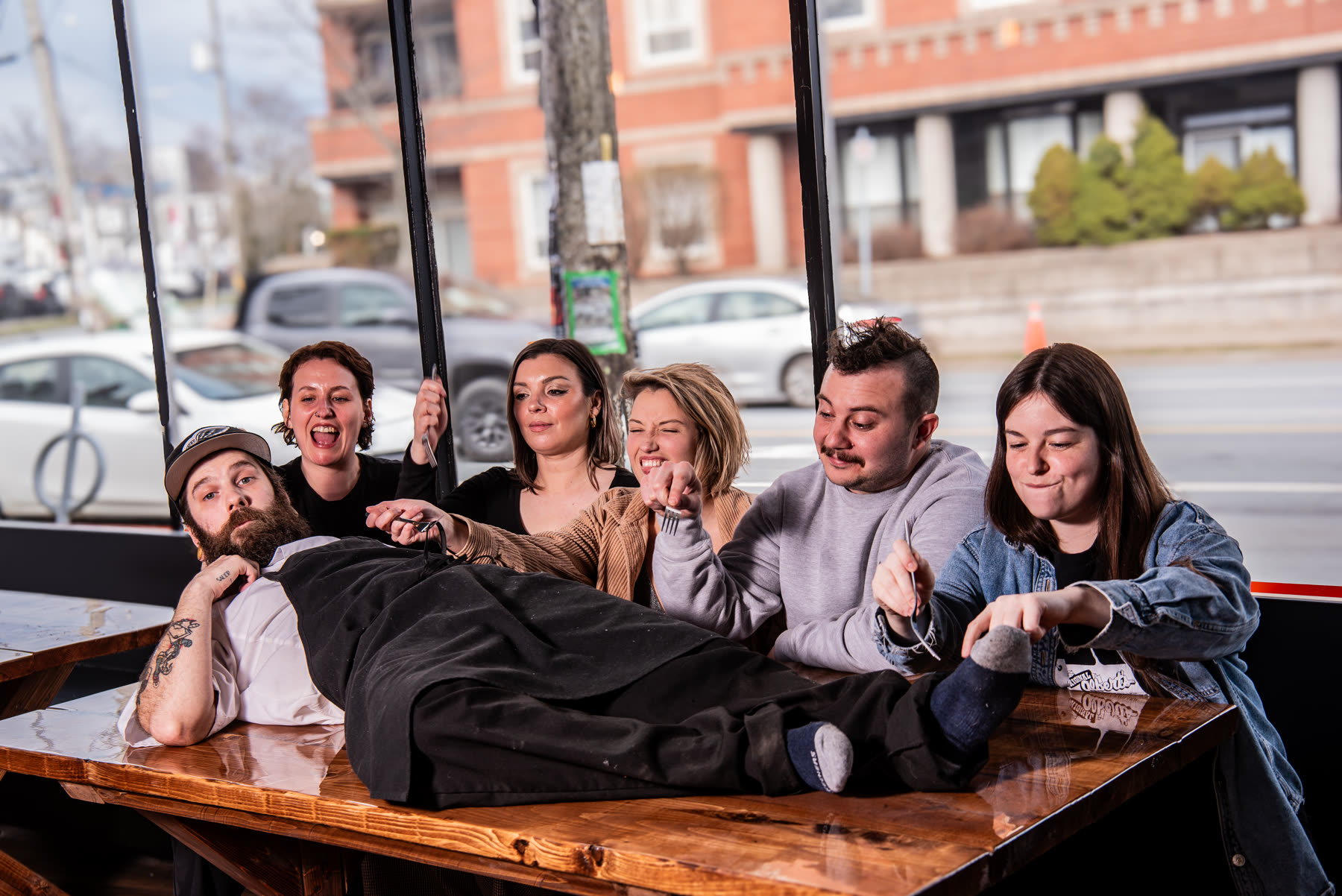 The Bonfire crew goofing around at one of their wooden tables by the window
